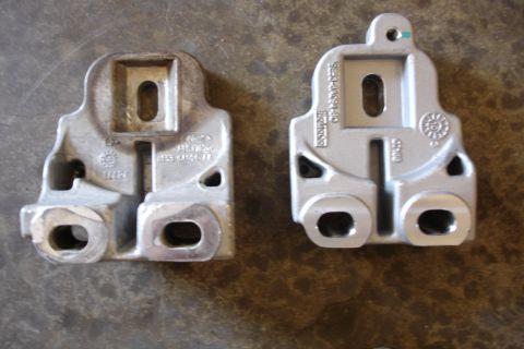 2006 Ford Fusion - Two metal mounting brackets, one showing Ford branding, are displayed on a gray, textured surface.