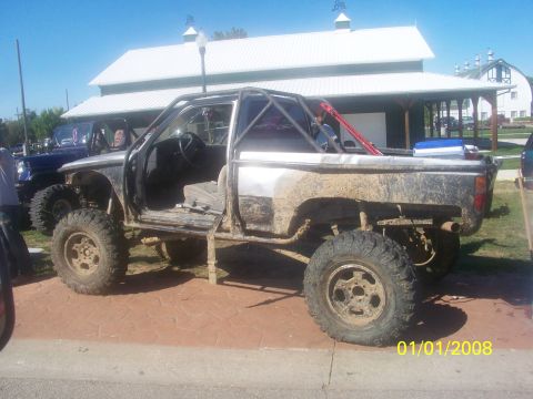 1989 Ford Bronco - This heavily modified pickup truck appears to be set up for off-road use, with its doors removed and a roll cage installed.