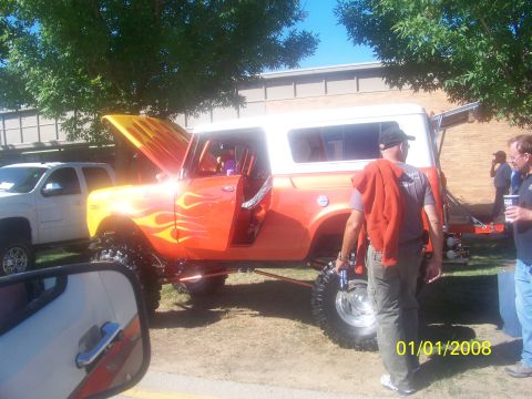 1989 Ford Bronco - This customized SUV features a vibrant flame paint job and significant suspension modifications, displayed outdoors.