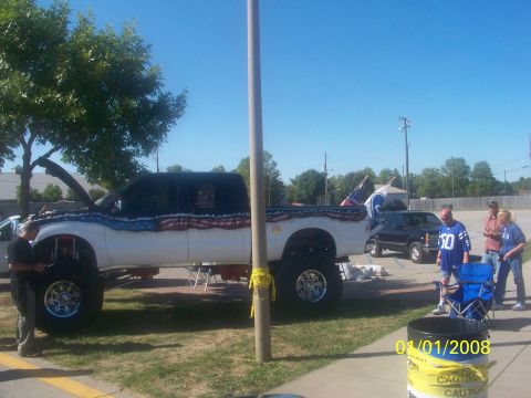 1989 Ford Bronco - A heavily modified pickup truck with patriotic paint is displayed at an outdoor event.