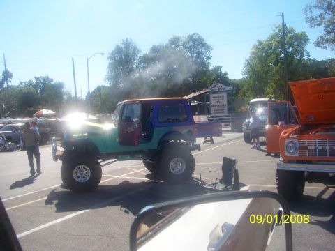 1989 Ford Bronco - A customized Jeep CJ and an orange Ford Bronco are parked at an outdoor event.