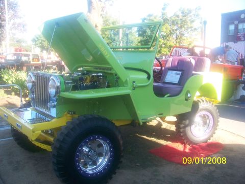 1989 Ford Bronco - A modified Willys Jeep is displayed with its hood open, revealing the engine bay.
