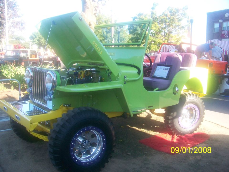 Lime green Willys Jeep with purple interior, hood open, chrome grille, yellow chassis, and custom wheels