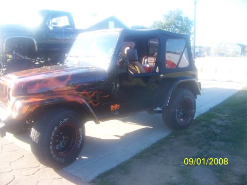 1989 Ford Bronco - A black Jeep Wrangler with flame graphics is parked next to a lifted truck.