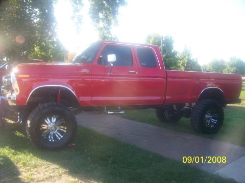 1989 Ford Bronco - This lifted red pickup truck is shown from the side.