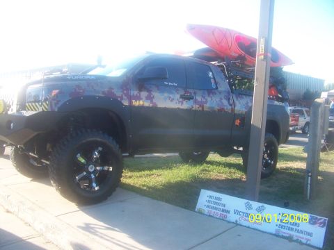 1989 Ford Bronco - This modified pickup truck features a unique digital camouflage wrap and is equipped with kayaks on its roof rack.