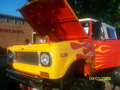 1989 Ford Bronco - This custom SUV features a vibrant flame paint job and its hood is open, revealing a stuffed toy.