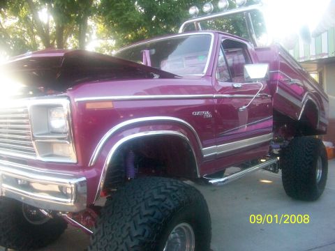 1989 Ford Bronco - This lifted pickup truck has custom paint and large off-road tires. The hood is open, revealing the engine bay.