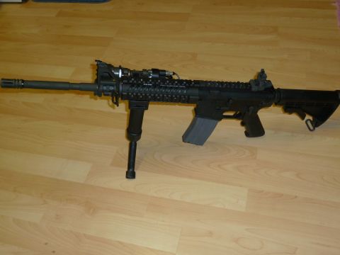 1992 Ford Mustang - An assault rifle with a bipod and extended magazine is displayed on a wooden floor.