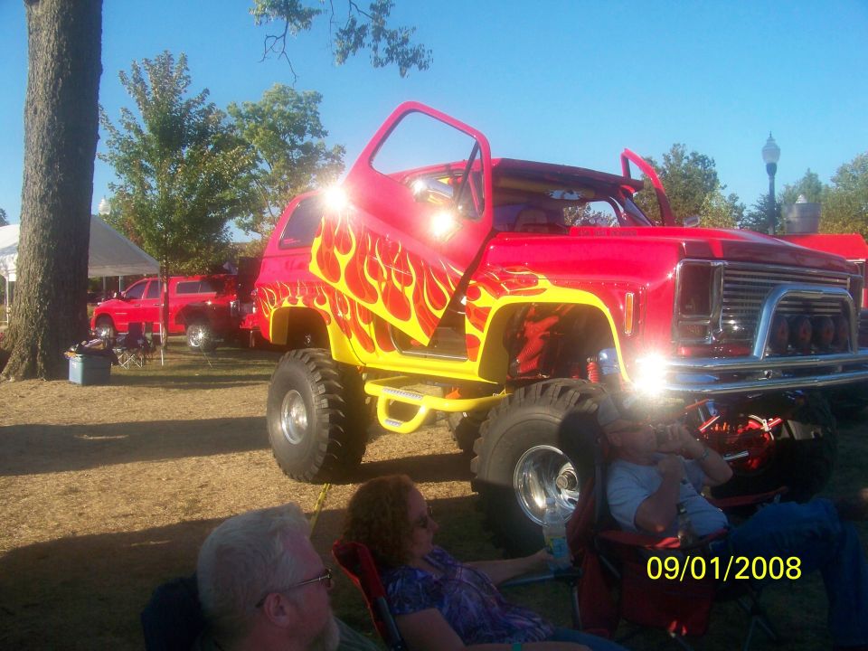 Red and yellow flame-painted lifted SUV with doors open, parked outdoors