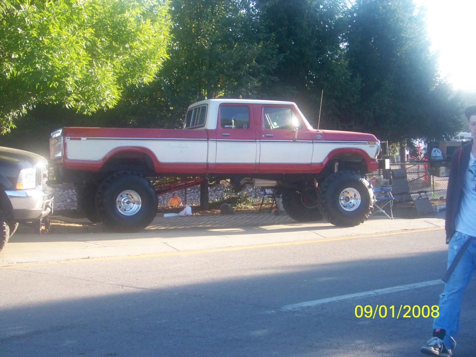 Side view of a lifted red and white pickup truck with large tires