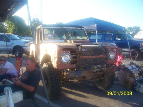1989 Ford Bronco - This weathered Ford Bronco, likely from the 1970s, sits ready for off-road adventure with its tires and custom grille.
