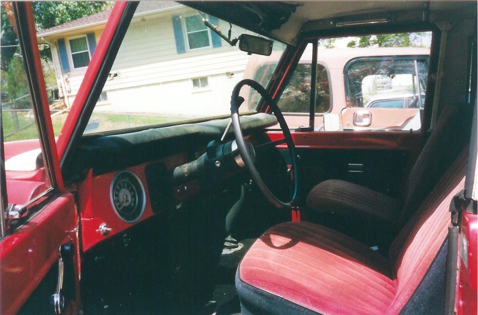 Red 1974 Ford Bronco interior with striped seats and a dashboard gauge