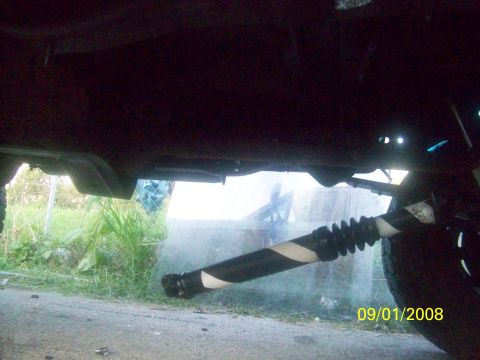 1989 Ford Bronco - The drive shaft of a vehicle is visible from underneath, a distinctive black and white striped pattern.
