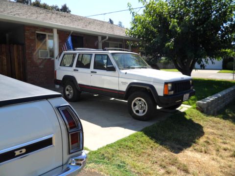 1994 Jeep Cherokee - A white 1994 Jeep Cherokee is parked in a driveway next to another vehicle.