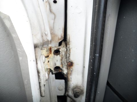 1994 Jeep Cherokee - Close-up of a corroded door hinge area on a vehicle, indicating potential structural damage.