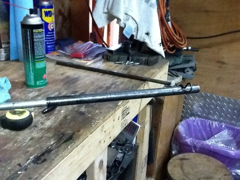 1988 Suzuki Samurai - A workbench is set up with various tools and parts, including a metal rod and a tape measure.