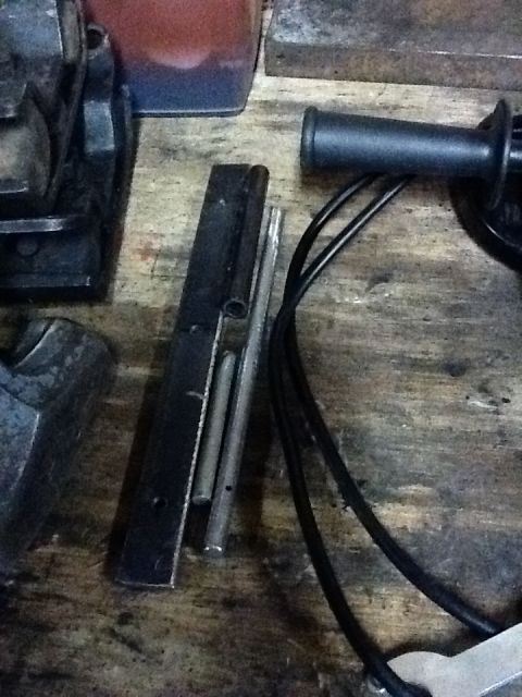 1988 Suzuki Samurai - Various metal parts and tools are arranged on a wooden surface, with a black handle and cables visible.
