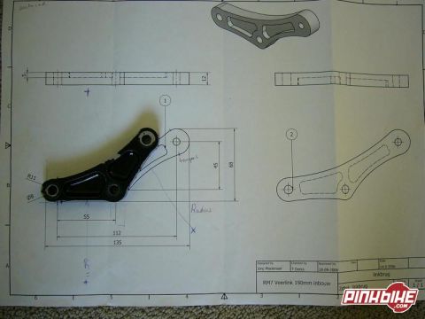 1973 Ford Ranchero - Dimensioned engineering blueprint of a suspension link bracket with a title block, with the actual machined part laid on the print.