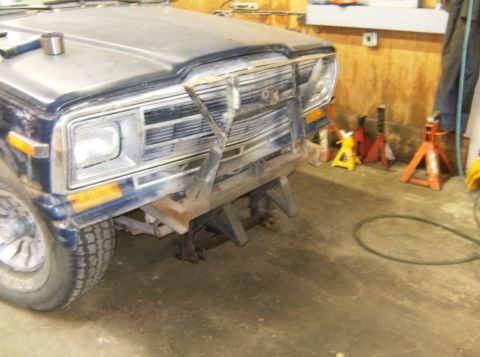 2000 Ford E350 - Van front on jack stands with a custom bumper and grille guard, showing a tire and headlight.