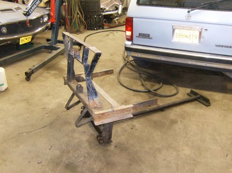 2000 Ford E350 - A metal frame assembly rests on the garage floor, with a car and a minivan visible in the background.