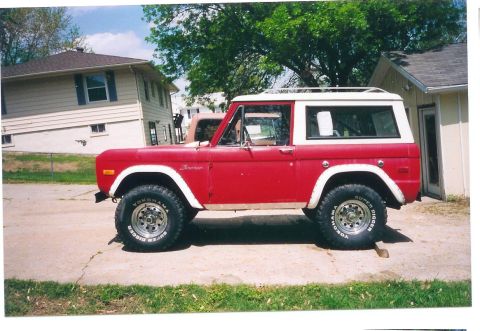 1974 Ford Bronco - Side view of a red 1974 Ford Bronco, a white hardtop and roof rack.