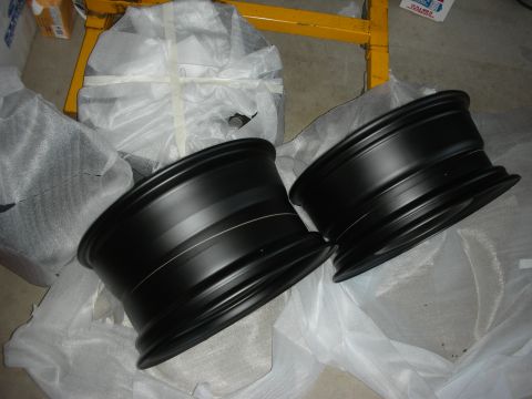 2004 Ford Crown Victoria - Two new black alloy wheels are shown, still in their protective packaging.
