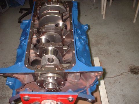 1969 Ford Mustang - Close-up of a blue engine block with a crankshaft, suggesting an automotive part.