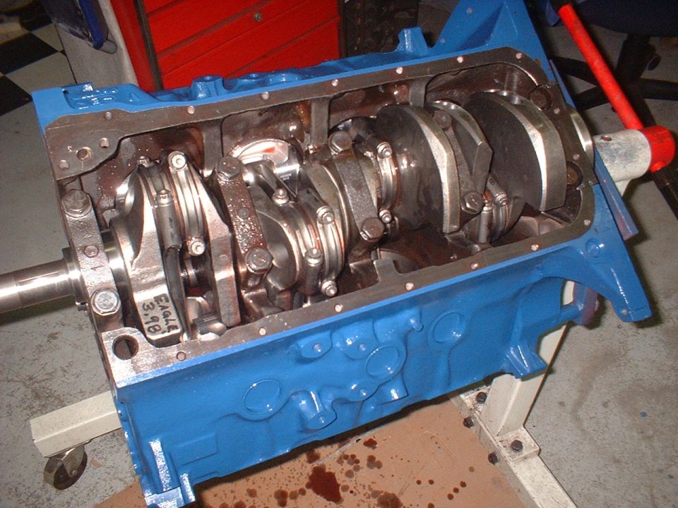 Blue engine block with crankshaft and connecting rods visible inside. "Eagle 3.98" is marked on a connecting rod