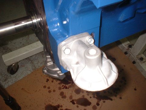 1969 Ford Mustang - Close-up of an engine block's oil filter housing and shaft, with oil stains visible on the floor.