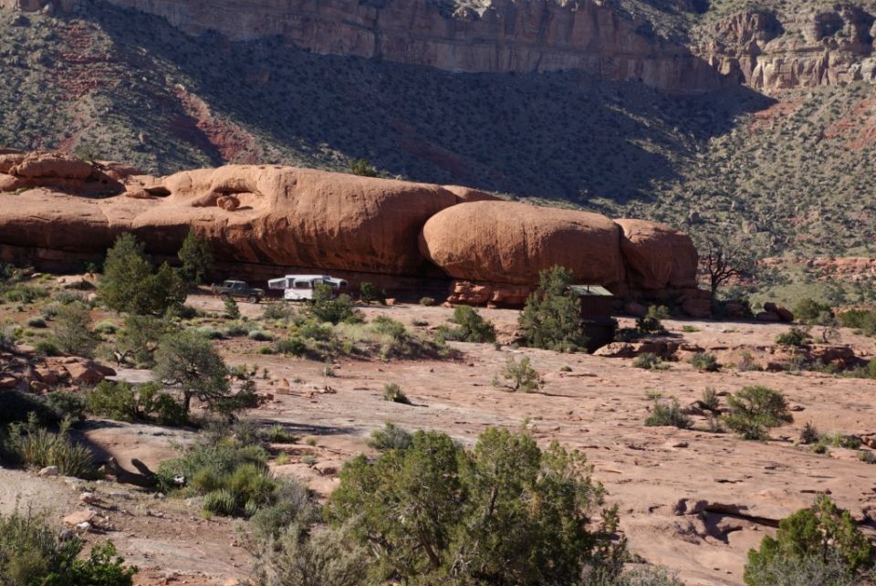 Camper trailer and SUV parked in a desert landscape with large rock formations
