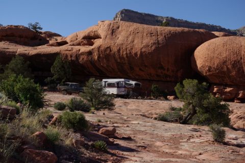 1995 Ford Bronco - A Ford Bronco and a pop-up camper are parked in a scenic desert location with large rock formations.