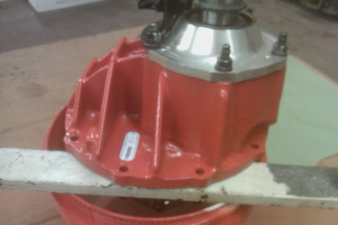 1999 Chevrolet Camaro - A close-up view of a red differential housing, likely a vehicle part, with visible bolts and a silver cap.