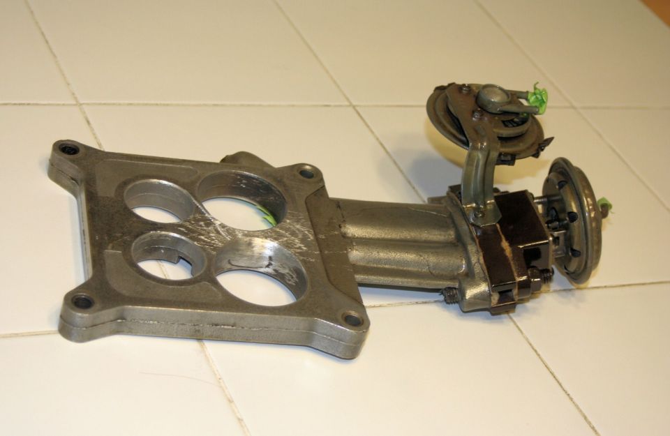 Carburetor base with four openings and attached linkage and vacuum pods