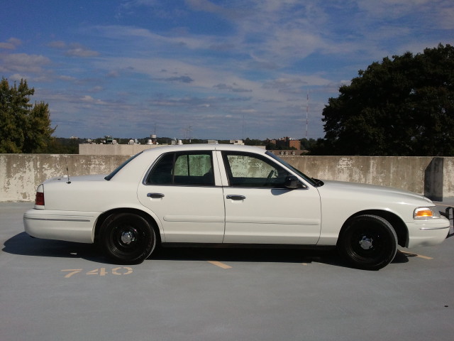 White sedan parked on a rooftop, side view. Black wheels