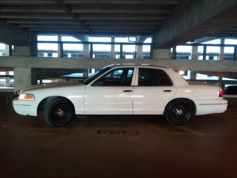 1998 Ford Crown Victoria - A white 1998 Ford Crown Victoria is parked in a garage, showing its side profile with black wheels.