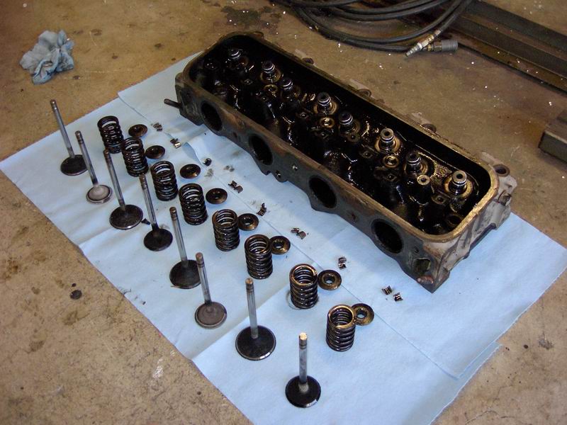 Disassembled cylinder head with valves, springs, and keepers laid out on paper