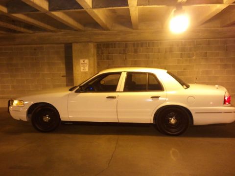 1998 Ford Crown Victoria - A white 1998 Ford Crown Victoria is seen from the side in an indoor parking area.