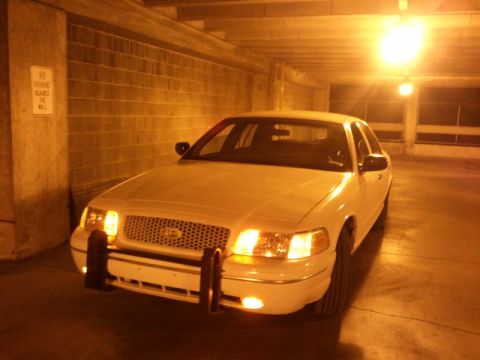1998 Ford Crown Victoria - Front view of a white 1998 Ford Crown Victoria with a push bumper, parked indoors.