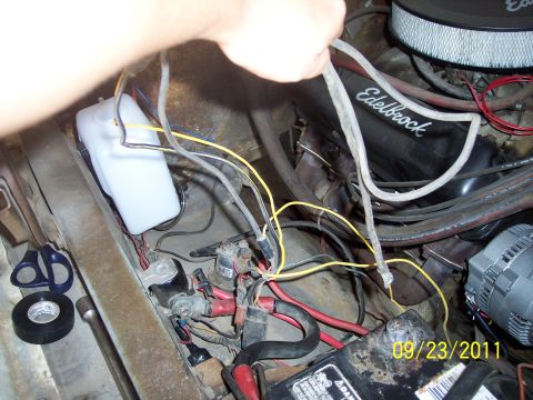 1973 Ford F-250 - A person is working on the wiring in the engine bay of a vehicle, with tools and electrical components visible.