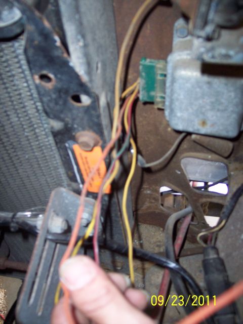 1973 Ford F-250 - Close-up view of an engine wiring harness, showing various colored wires and a green electrical connector, with an orange label attached.