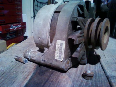 1973 Ford F-250 - An old alternator sits on a wooden surface, with a label showing a 1973 date code.