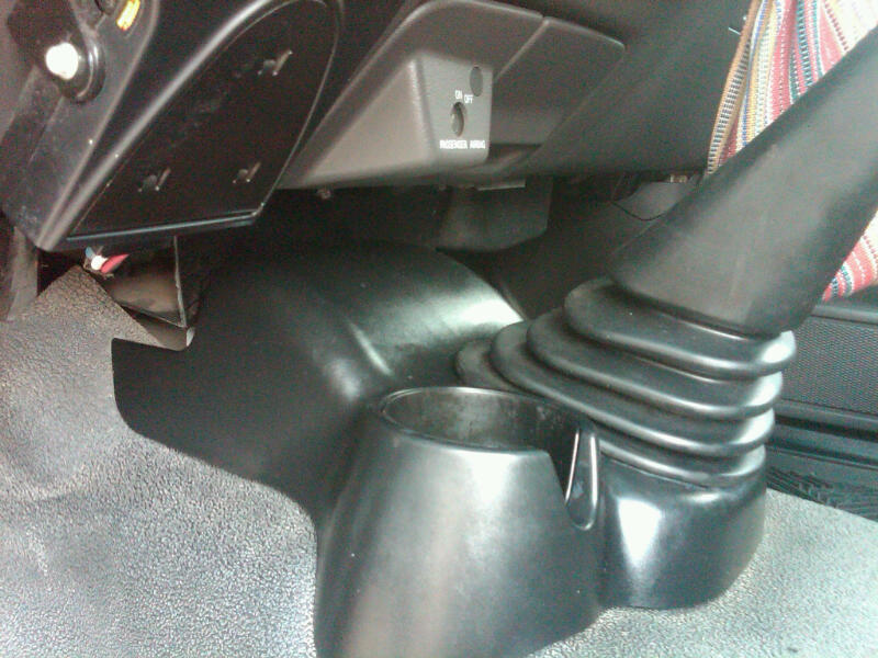 Black center console with cup holder and gear shifter boot, passenger side air bag switch visible