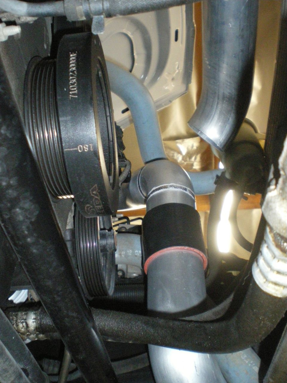 Engine bay with supercharger components, including a pulley and hose assembly