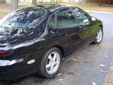 1999 Ford Taurus - This black 1999 Ford Taurus sedan is viewed from the side, showing its distinctive body style.