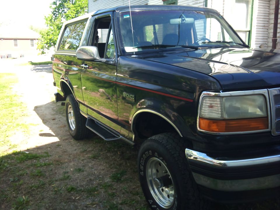 1994 Ford Bronco parked next to a house, showing the front 3/4 view