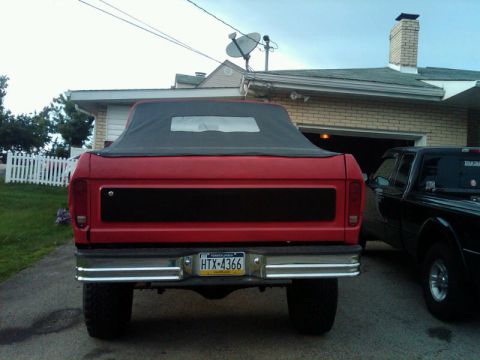1979 Ford Bronco - The rear of a red soft-top SUV is shown, with a black panel across the tailgate and a Pennsylvania license plate.