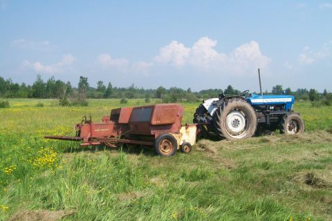 2000 Chevrolet Tahoe - Tractor and hay baler working in a field on a sunny day.