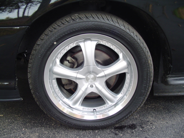 close-up of a silver 5-spoke aftermarket wheel on a black car