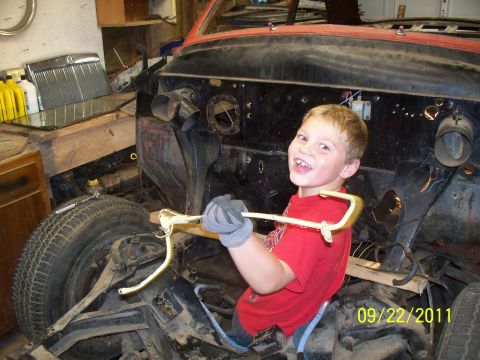 1990 Ford Bronco - A young boy smiles while holding a tool inside a vehicle undergoing restoration.